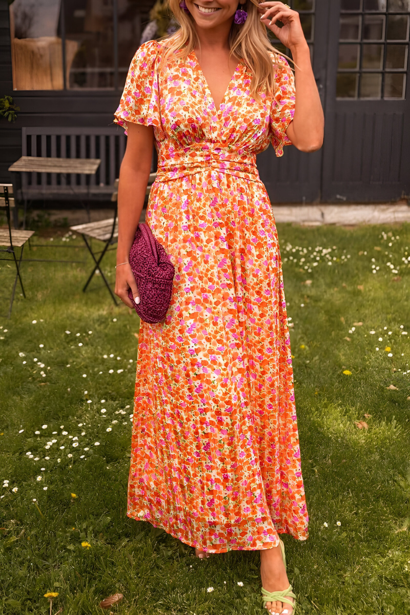 Robe longue à col en V pour femme, modèle tendance. Ce modèle élégant et coloré présente un motif floral vibrant dans des tons de rose, orange et jaune. La robe est complétée par des accessoires modernes, comme un sac en crochet violet et des boucles d'oreilles assorties. Un look parfait pour une occasion estivale, alliant confort et style.