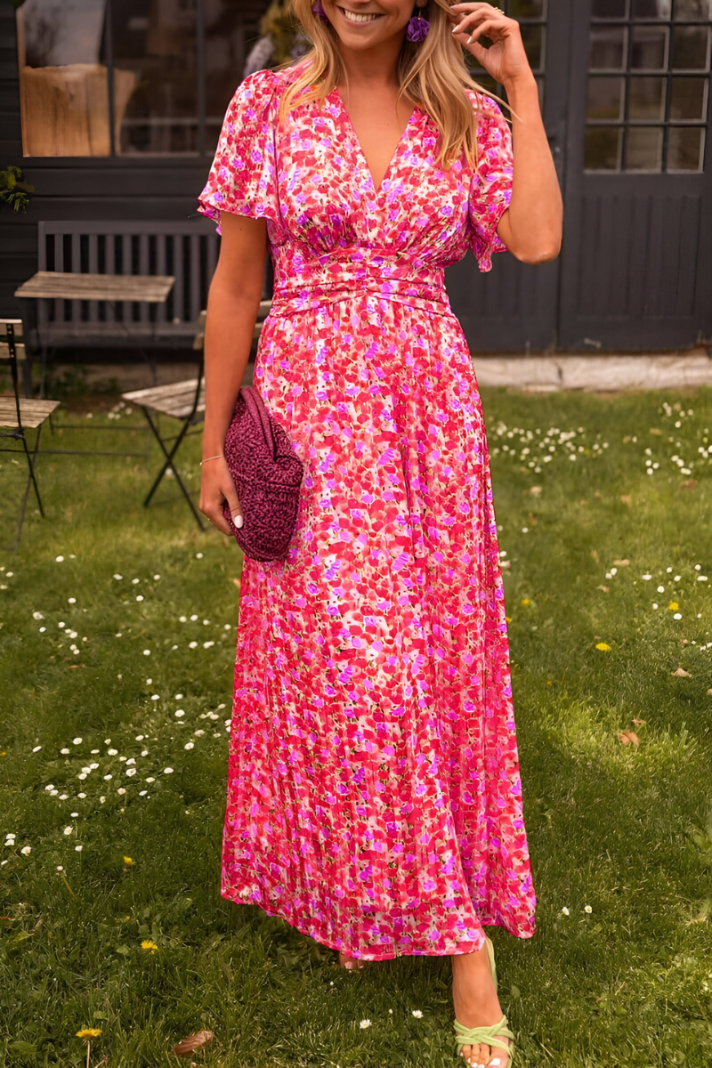Cette robe légère et fluide est décorée d'un motif floral vibrant dans des tons de rose et fuchsia, parfaite pour les journées d'été. Elle est complétée par un sac en crochet violet et des boucles d'oreilles assorties, offrant un look à la fois élégant et décontracté.