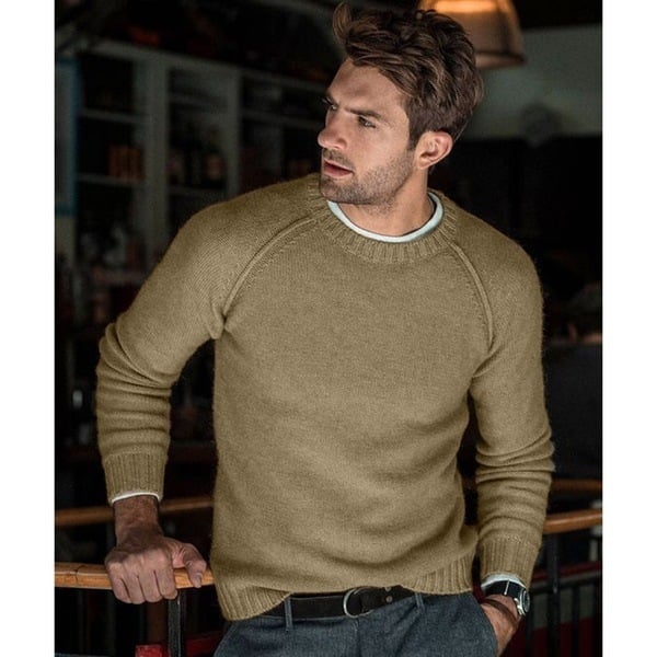 Un homme portant un pull long oversize à manches raglan, associé à un pantalon et une ceinture.