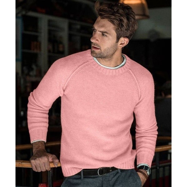 Un homme portant un pull long oversize à manches raglan et coupe décontractée, associé à un pantalon.