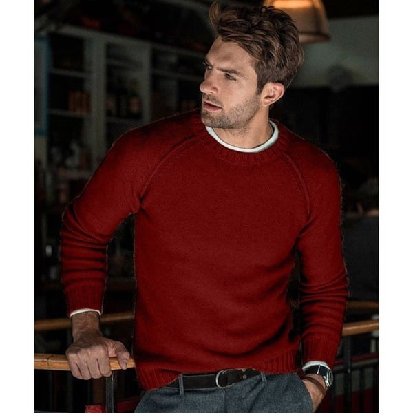 Un homme portant un pull long oversize à coupe décontractée et manches raglan, associé à un pantalon.