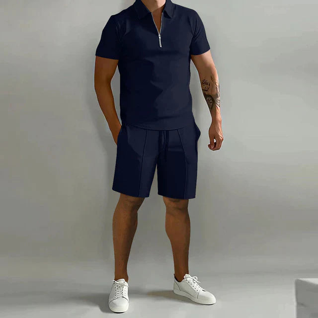 Homme portant l’ensemble Rupert bleu marine avec polo zippé à manches courtes et short assorti, idéal pour un look d’été moderne, sportif et décontracté.