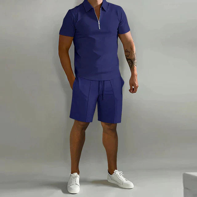 Homme portant l’ensemble Rupert bleu marine avec polo zippé à manches courtes et short assorti, idéal pour un look d’été moderne et décontracté.