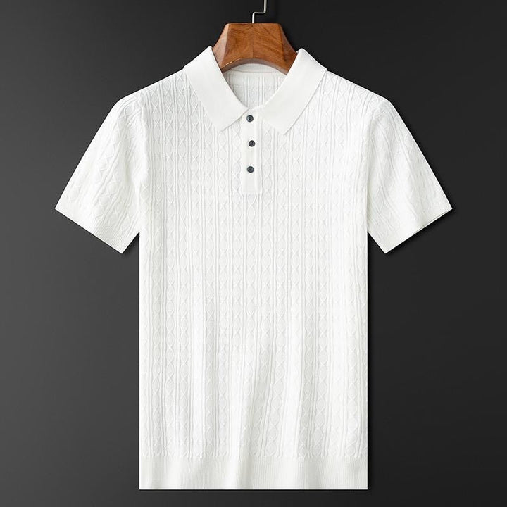 Polo premium pour homme Sabin, blanc élégant à manches courtes, suspendu sur cintre, avec col classique et patte de boutonnage, offrant une texture raffinée et un style moderne et tendance.