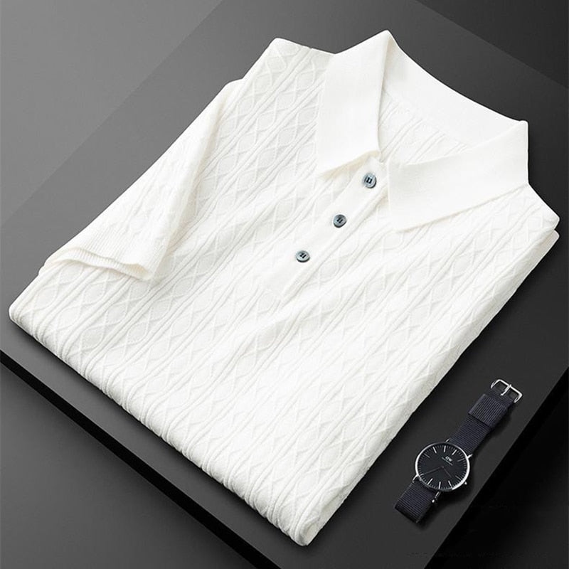 Polo premium pour homme Sabin, couleur blanc cassé, plié avec soin, doté d’un col classique et de boutons élégants, présentant une texture raffinée et tendance, accompagné d’une montre moderne pour un style chic et sophistiqué.