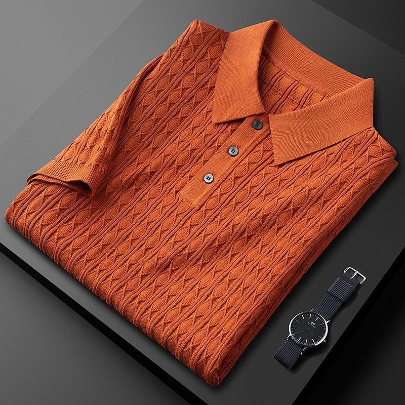 Polo premium pour homme Sabin, couleur terracotta élégante avec texture en maille travaillée, plié avec soin, doté d’un col classique et de boutons discrets, accompagné d’une montre moderne pour un style tendance et sophistiqué.