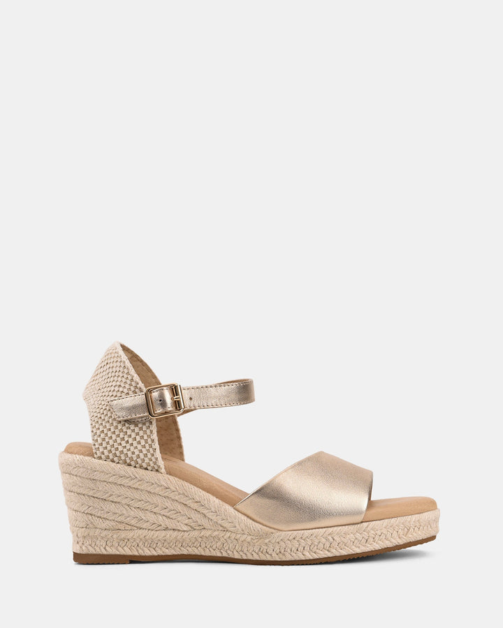 Vue latérale des sandales compensées dorées pour femmes, avec bride avant métallisée et sangle de cheville à boucle. Talon compensé en corde tressée style espadrille, offrant un équilibre parfait entre confort et style moderne.