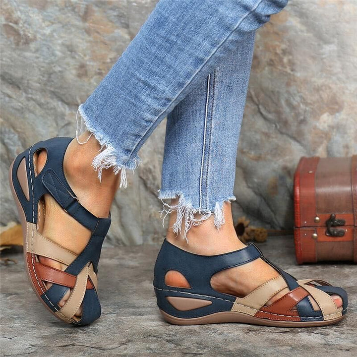 Sandales de marche fermées pour femme en cuir bicolore bleu marine, beige et marron, design ajouré, semelle confortable, portées avec un jean.