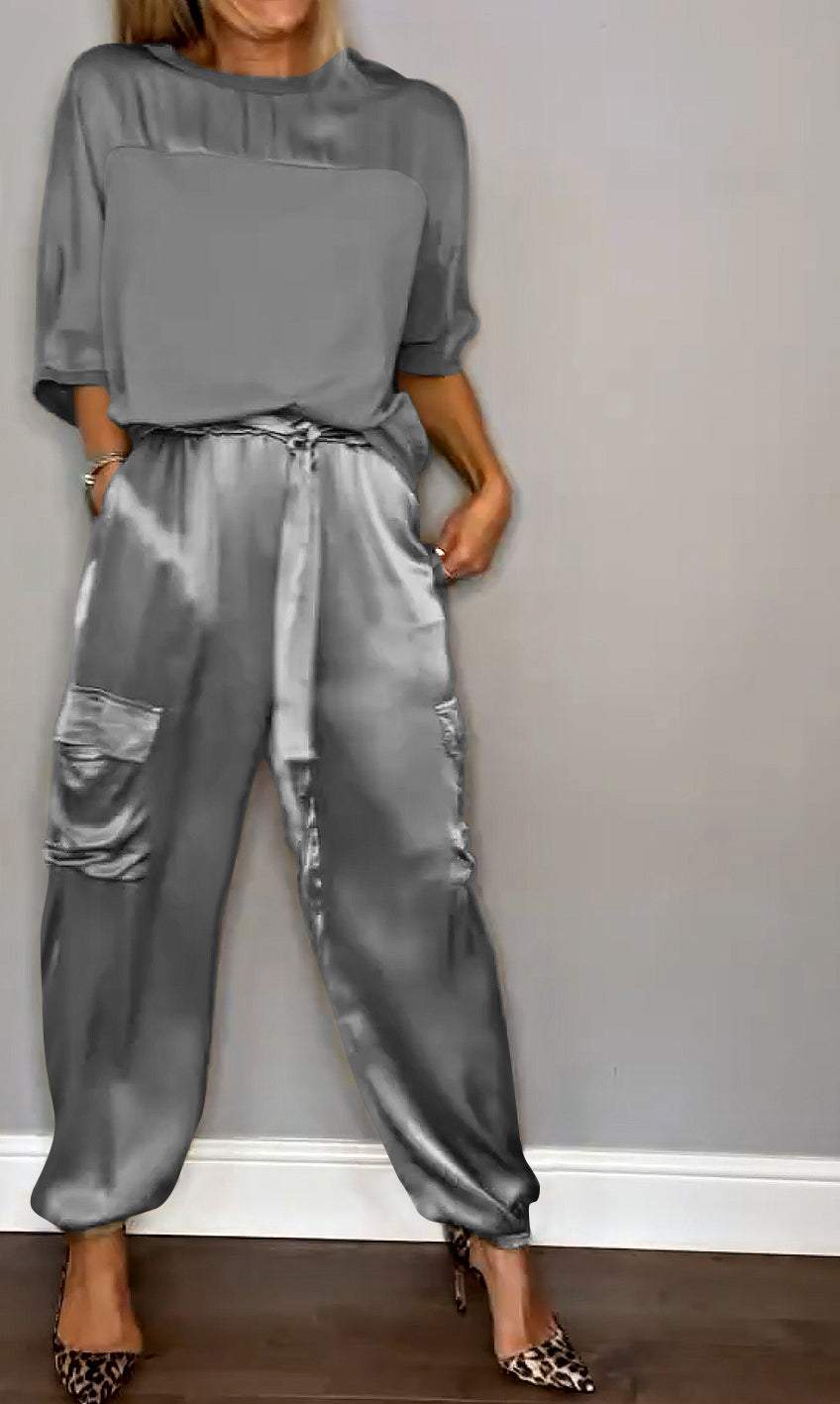 Femme portant un ensemble élégant composé d'un haut fluide gris et d'un pantalon cargo satiné avec des poches latérales. Elle porte des escarpins léopard, créant un look à la fois sophistiqué et décontracté.