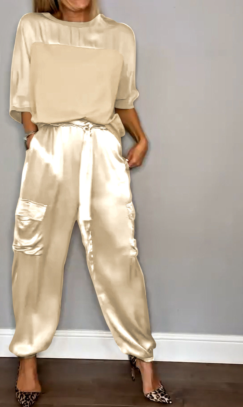Femme portant un ensemble élégant avec un haut fluide beige et un pantalon cargo satiné dans des tons similaires, orné de poches latérales. Elle porte des escarpins léopard, créant une silhouette sophistiquée et décontractée.