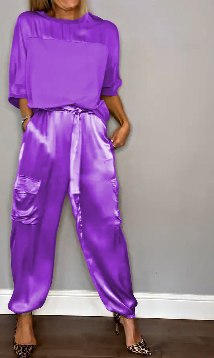 Femme portant un ensemble élégant en violet, composé d'un haut fluide et d'un pantalon cargo satiné avec des poches latérales. Elle porte des escarpins léopard, créant un look à la fois sophistiqué et moderne.