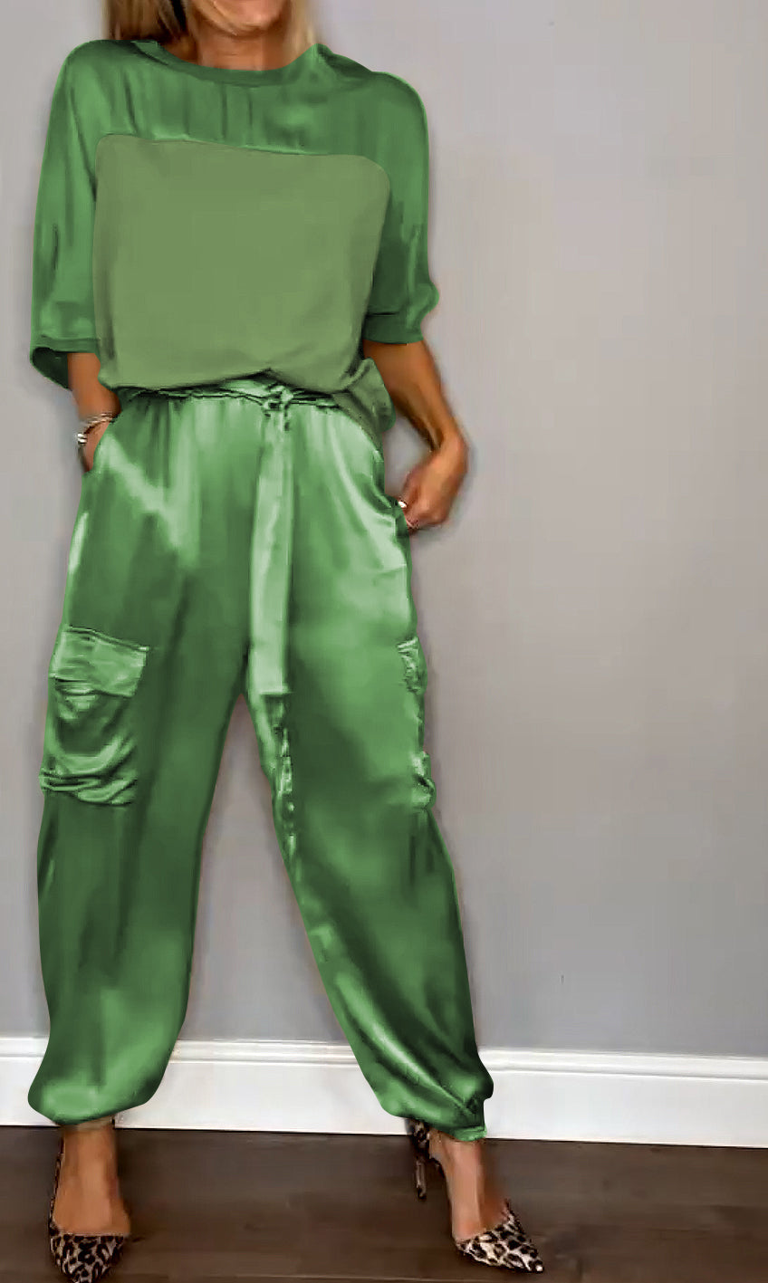 Femme portant un ensemble élégant en vert, composé d'un haut fluide et d'un pantalon cargo satiné avec des poches latérales. Elle porte des escarpins léopard, créant un look sophistiqué et moderne.