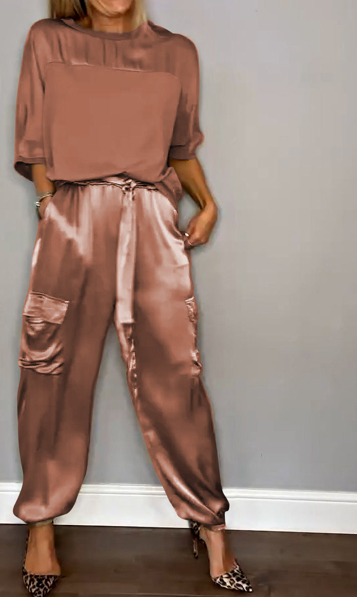Femme portant un ensemble élégant rose pâle, composé d'un haut fluide et d'un pantalon cargo satiné avec des poches latérales. Elle porte des escarpins léopard, créant un look à la fois raffiné et moderne.