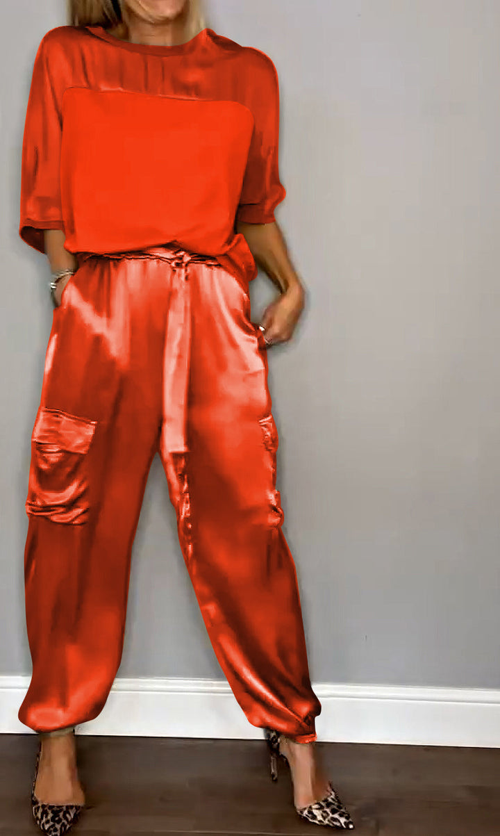 Femme portant un ensemble élégant beige, composé d'un haut fluide et d'un pantalon cargo satiné avec des poches latérales. Elle porte des escarpins léopard, créant un look raffiné et moderne.