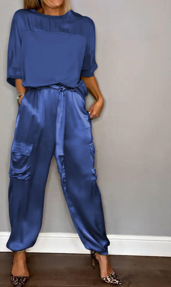 Femme portant un ensemble élégant bleu, composé d'un haut fluide et d'un pantalon cargo satiné avec des poches latérales. Elle porte des escarpins léopard, créant un look sophistiqué et moderne.