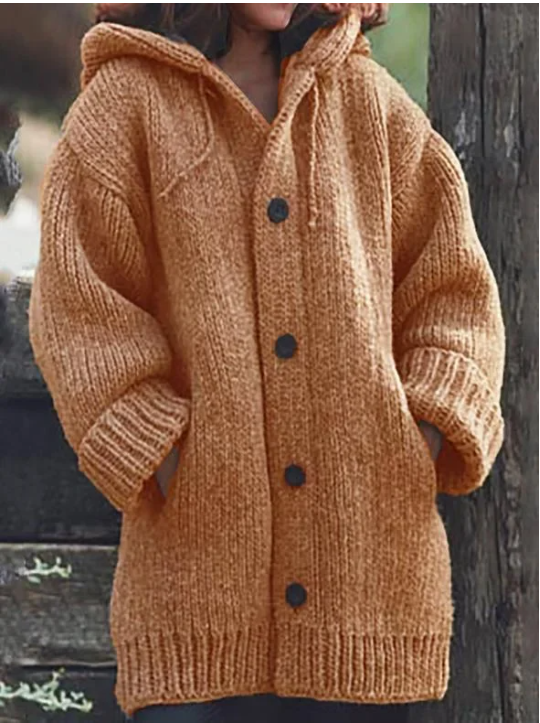 Femme portant un long cardigan épais orange caramel à manches larges, poches latérales et gros boutons foncés, offrant un style hivernal chaud et décontracté.