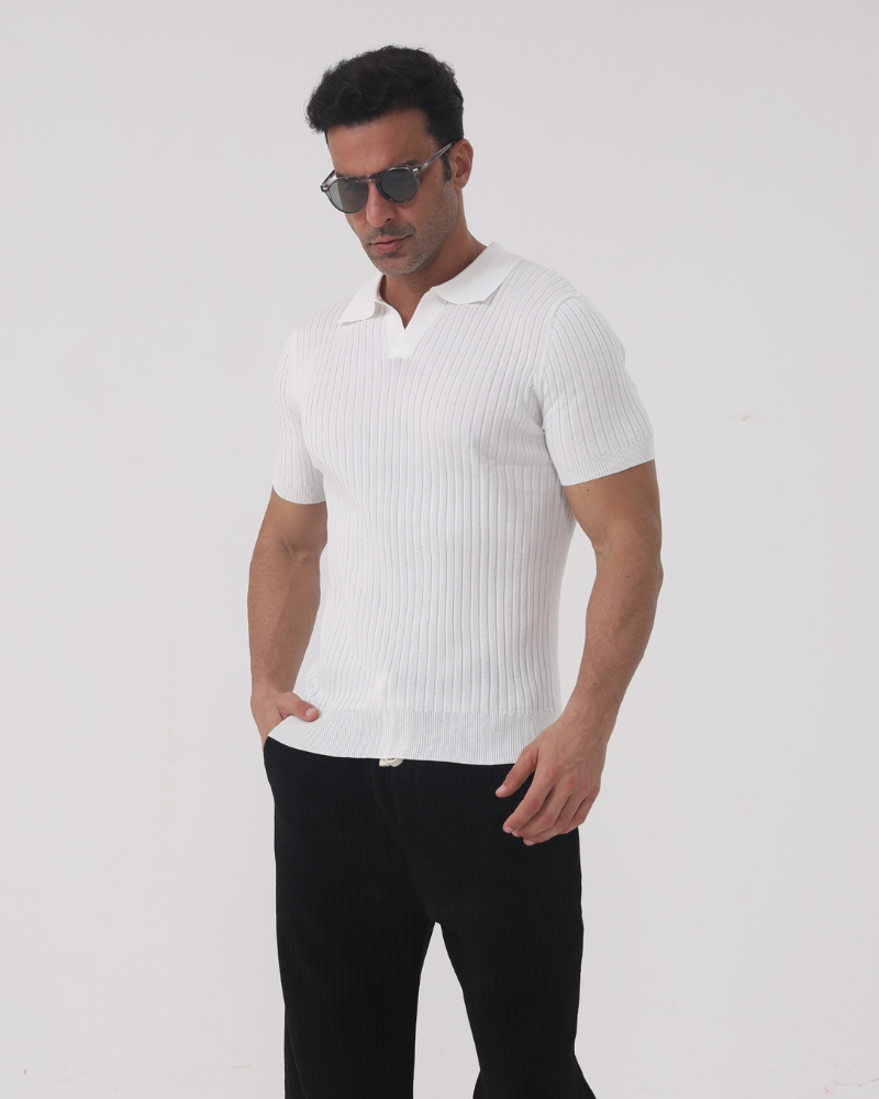 Homme portant le polo Sully en maille côtelée blanc, à manches courtes avec col en V, coupe ajustée, associé à un pantalon sombre et des lunettes de soleil, pour un style moderne et tendance.