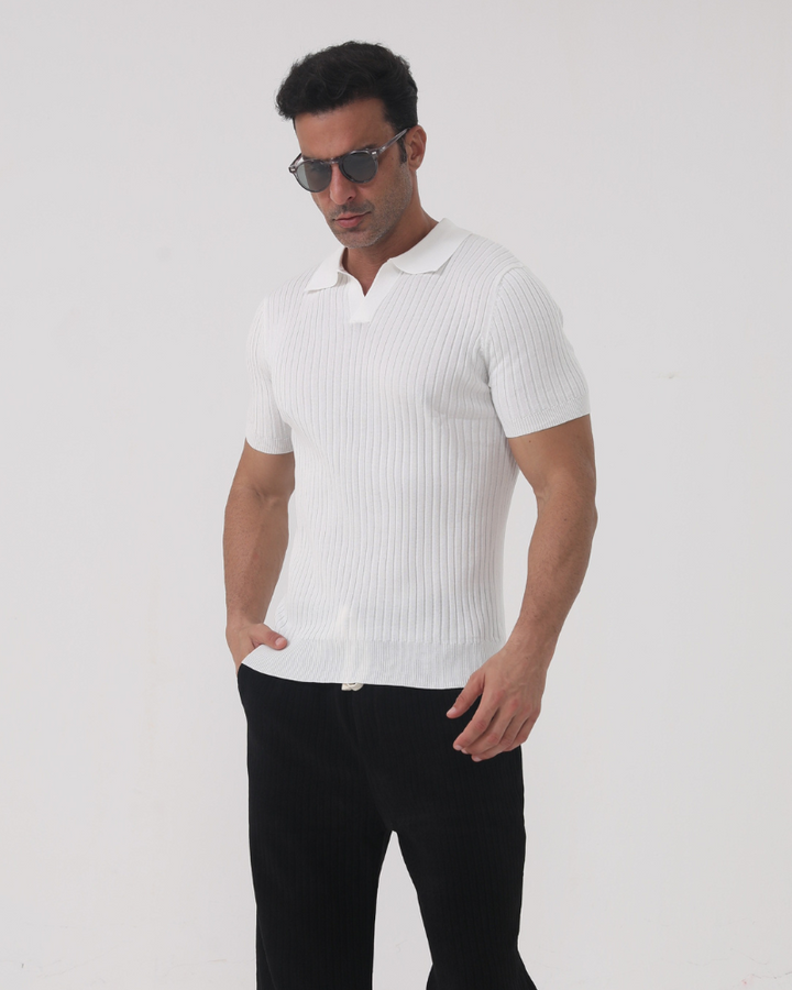 Homme portant le polo Sully en maille côtelée blanc, à manches courtes avec col en V, coupe ajustée, associé à un pantalon sombre et des lunettes de soleil, pour un style moderne et tendance.
