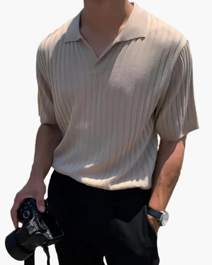 Homme portant le polo Sully en maille côtelée beige, à manches courtes avec col en V, offrant une texture élégante et un style moderne et tendance, associé à un pantalon sombre et une montre.