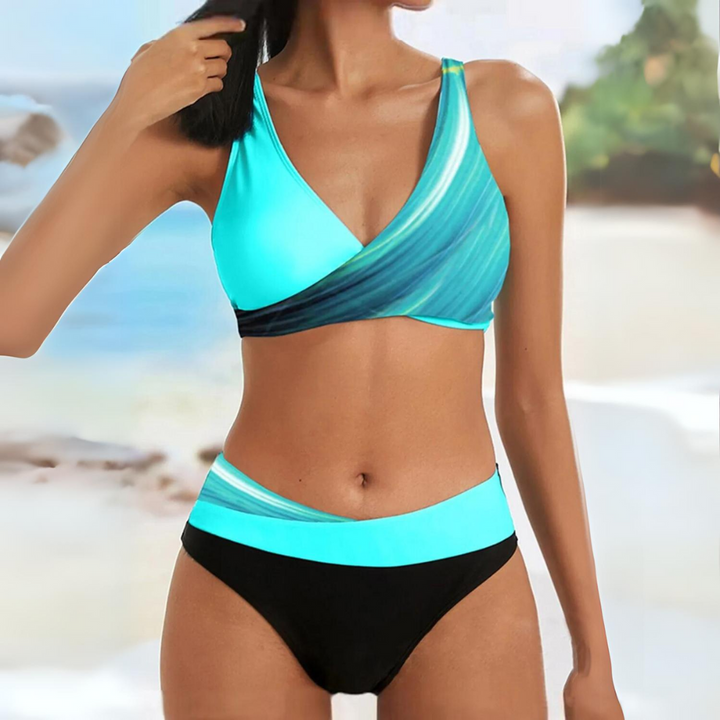 Ensemble bikini bleu turquoise avec un top croisé décoré de dégradés de couleurs et une culotte noire assortie. Ce bikini moderne et élégant est parfait pour un look frais et tendance à la plage ou à la piscine.