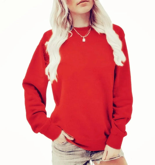Femme portant un sweat-shirt rouge vif à manches longues, avec un col rond. Elle a des cheveux blonds et porte un collier délicat, associant le sweat avec un short en jean. Elle pose une main sur sa taille.