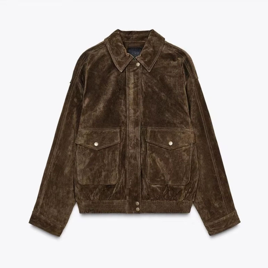 Veste en daim marron avec des poches avant à rabat, un col classique et une finition élastiquée au bas, offrant un style décontracté et tendance.