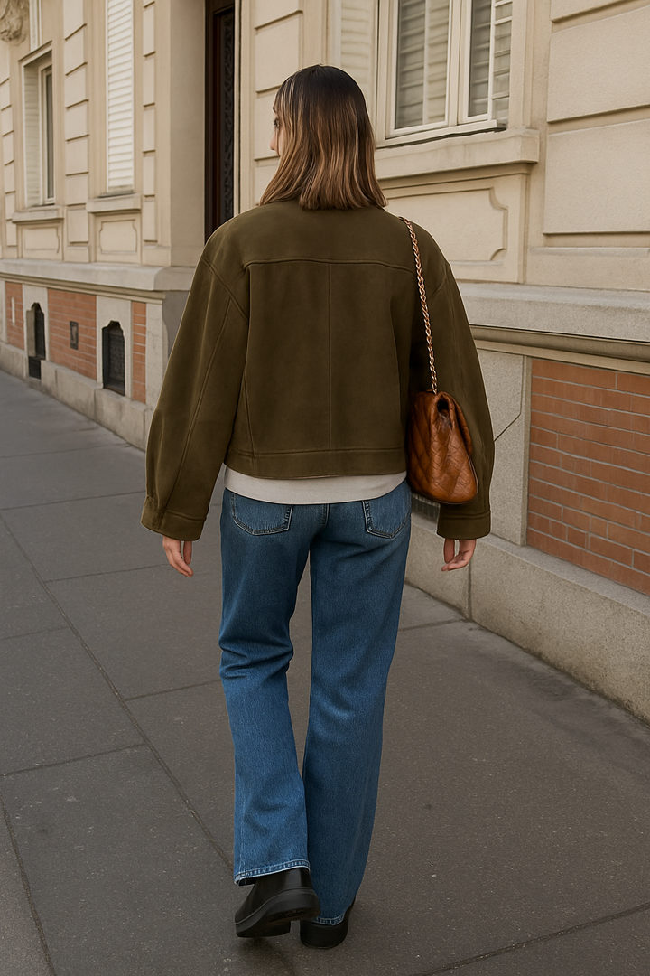 Vue arrière de la veste en daim olive portée avec un sweat beige, un jean bleu clair et des bottines noires. Complétée par un sac en cuir tressé, créant un look chic et décontracté.