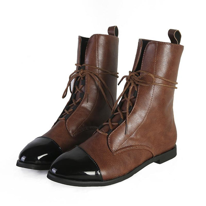 Paire de bottines cheville pour femme en cuir marron avec lacets, bout noir verni et semelle plate, présentées sur fond blanc, au style tendance et élégant pour l’automne et l’hiver.
