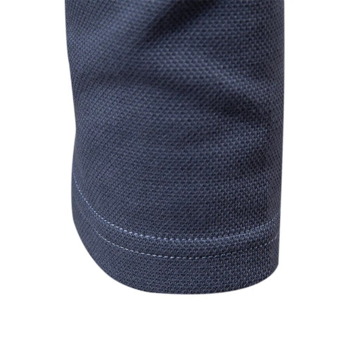 Détail du bas de manche du polo homme bleu, avec une finition soignée et une couture discrète, soulignant la coupe moderne et élégante.