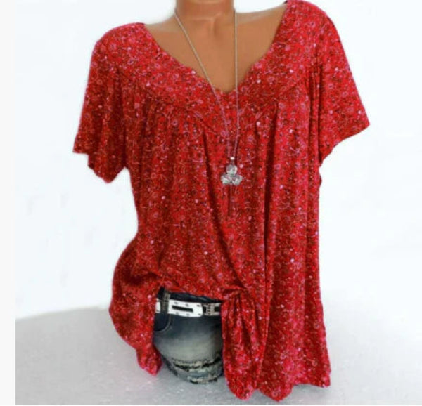Blouse Verity pour femme à manches courtes, coupe ample et fluide avec col V, imprimé fleuri moderne rouge, portée avec un jean  style décontracté et tendance.
