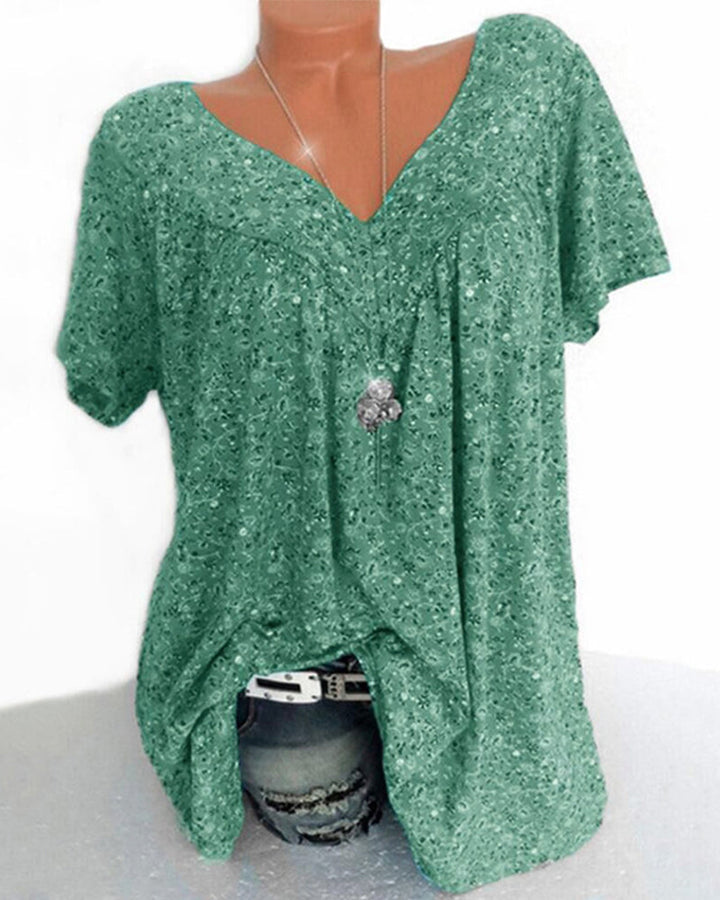 Blouse Verity pour femme à manches courtes, coupe ample et fluide avec col V, imprimé fleuri moderne vert, portée avec un jean  style décontracté, moderne et élégant.