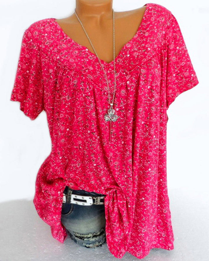 Blouse Verity pour femme à manches courtes, coupe ample et fluide avec col V, imprimé fleuri moderne fuchsia/rose vif, portée avec un jean  look tendance, féminin et décontracté.