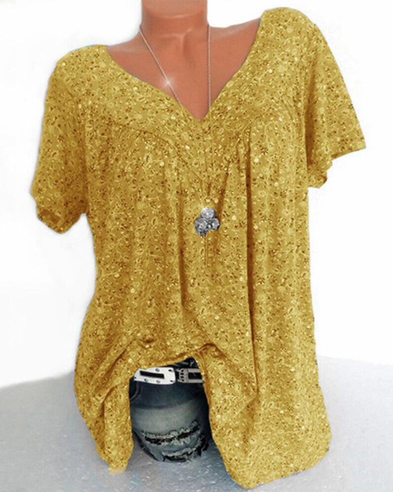 Blouse Verity pour femme à manches courtes, coupe ample et fluide avec col V, imprimé fleuri moderne jaune moutarde, portée avec un jean  style moderne, décontracté et élégant.