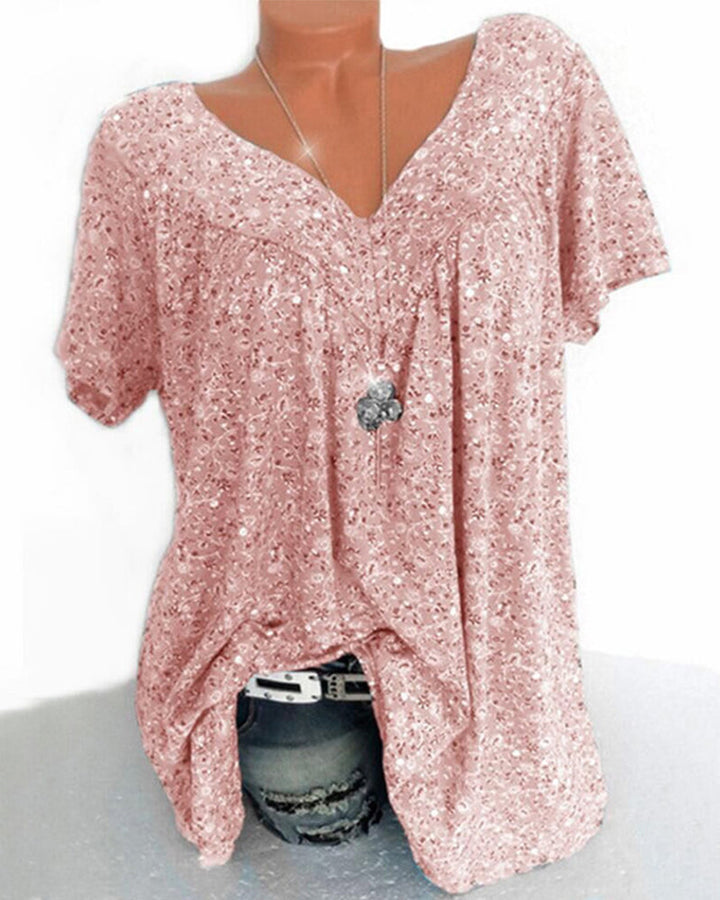 Blouse Verity pour femme à manches courtes, coupe ample et fluide avec col V, imprimé fleuri moderne rose poudré, portée avec un jean  look doux, féminin et tendance.