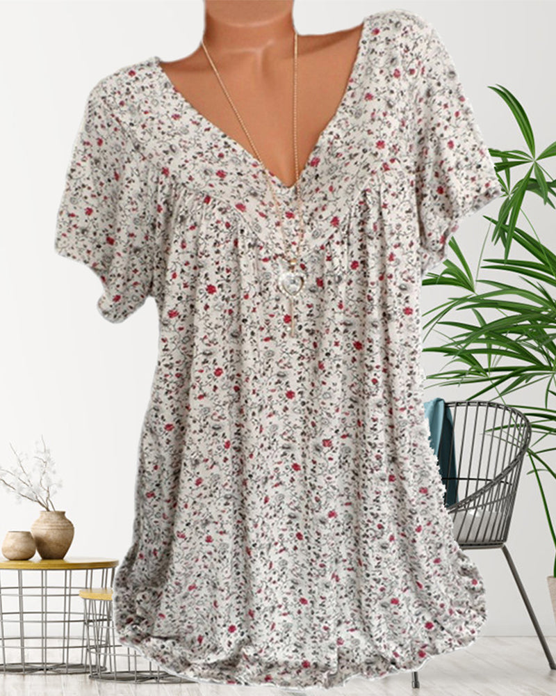Blouse Verity pour femme à manches courtes, coupe ample et fluide avec col V, imprimé fleuri moderne beige clair (petites fleurs rouges), portée avec un jean  look élégant et décontracté, photo en intérieur.