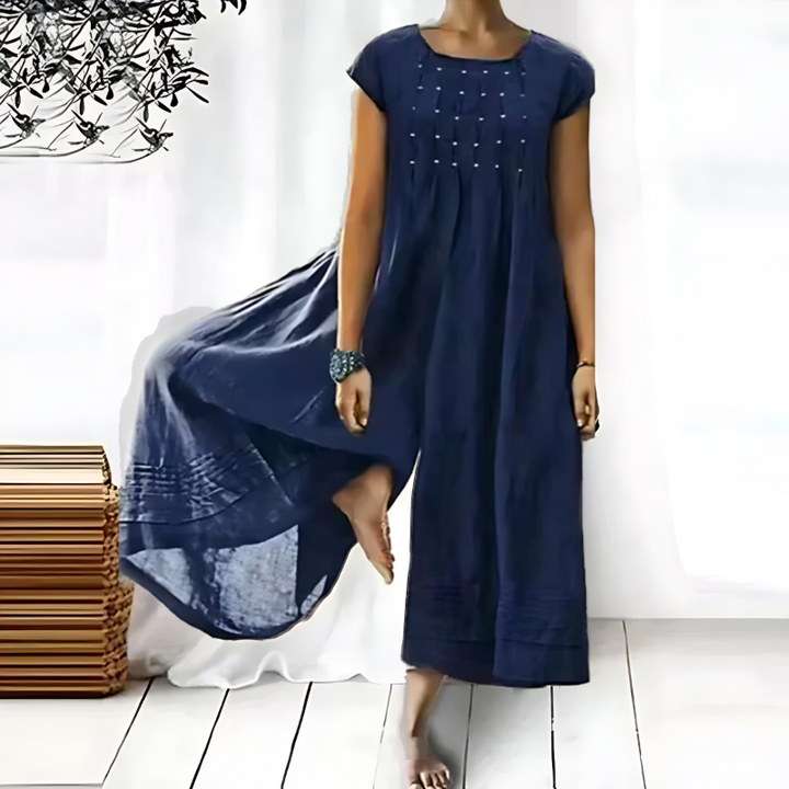 Une robe longue et fluide pour femme, de couleur bleu marine, avec des broderies délicates sur le devant, offrant une silhouette élégante et confortable, parfaite pour les occasions estivales.