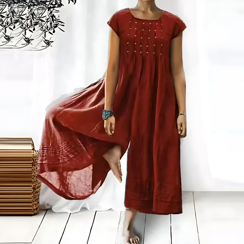 Une robe longue et fluide pour femme, de couleur rouge brique, avec des broderies délicates sur le devant, créant une silhouette élégante et décontractée, parfaite pour les journées d'été.