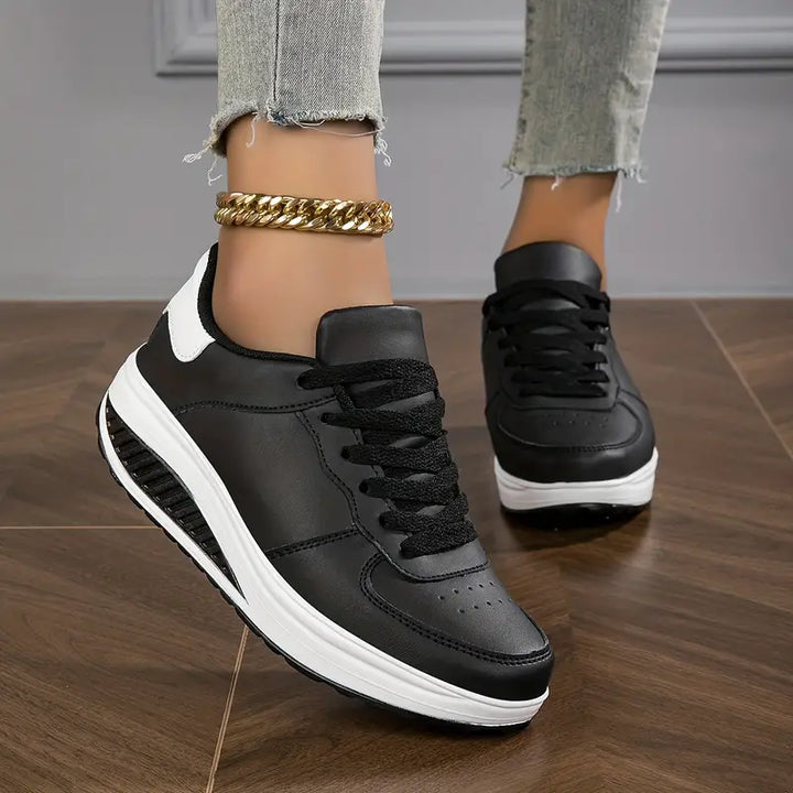 Baskets plates pour femme noires à lacets, avec détail blanc sur le côté et semelle épaisse blanche, portées avec un jean.