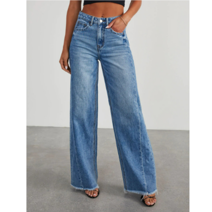 Pantalon taille haute Winifred pour femme en jean bleu délavé, coupe large tendance, porté avec un haut noir et des sandales, vue de face.