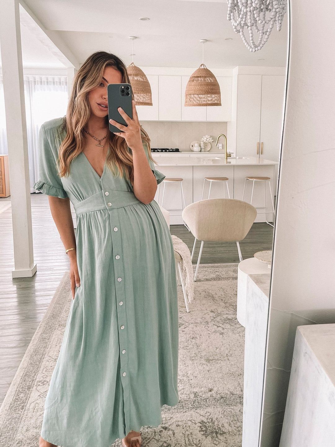 Robe midi d'été Wren pour femme, vue en selfie dans un miroir. Le modèle porte la robe à manches à volants avec des boutons sur le devant, offrant un look estival élégant et confortable dans un cadre lumineux et moderne.