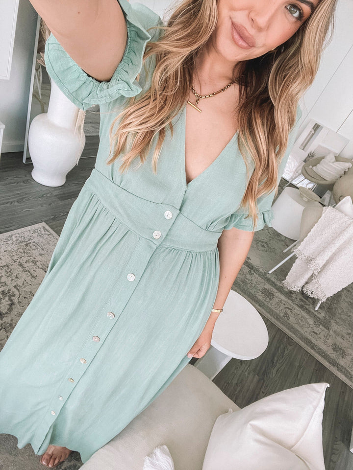 Robe midi d'été Wren pour femme, vue portée par un modèle avec des manches à volants et des boutons sur le devant. Design élégant et léger, parfait pour un look estival chic et confortable.