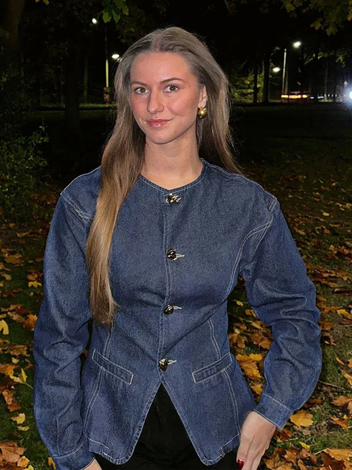 veste en jean bleu foncé à boutons argentés et pantalon assorti, silhouette hivernale chic, en rue urbaine avec cabine téléphonique rouge en arrière-plan et feuilles d’automne au sol.