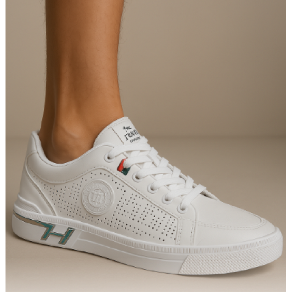Gros plan des baskets urbaines pour hommes Yvan blanches, style moderne avec perforations latérales, lacets blancs et petit détail tricolore, portées sur fond beige.