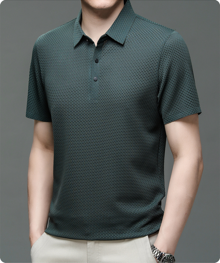 Un polo vert foncé en maille texturée, avec un col classique et des boutons noirs contrastés. Ce modèle élégant et confortable est idéal pour un look moderne et décontracté, parfait pour toutes les occasions.
