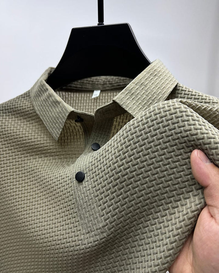 Gros plan sur un polo beige en maille texturée, avec un col classique et des boutons noirs contrastés. Ce polo élégant et moderne offre un style à la fois décontracté et raffiné, parfait pour toutes les occasions.