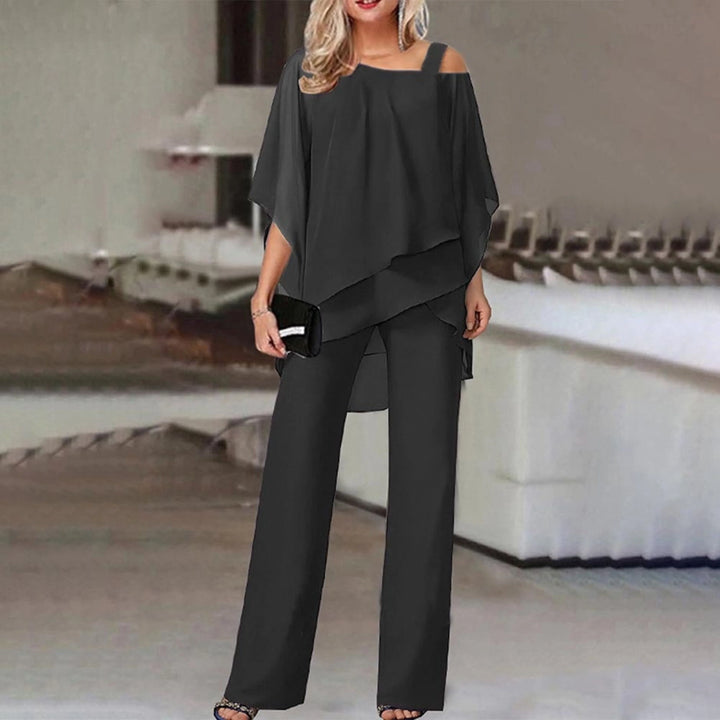 Optez pour l'élégance moderne avec l'ensemble Zahra en noir. Ce duo tendance se compose d'un haut fluide et asymétrique à manches ouvertes avec des bretelles décorées de strass, accompagné d'un pantalon large pour une silhouette chic et confortable. Parfait pour une soirée ou une occasion spéciale, cet ensemble allie raffinement et style.