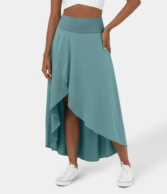 Jupe fluide et légère en coloris vert bleu, avec une coupe asymétrique et une fente subtile sur le côté. Un modèle élégant et confortable, parfait pour un look estival moderne avec des baskets ou des sandales.