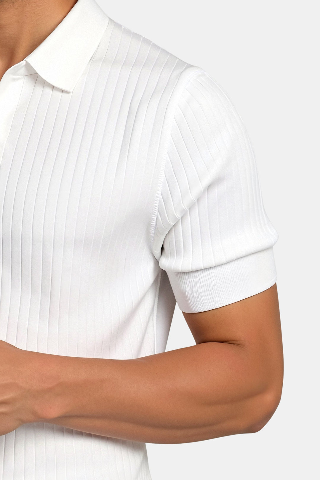 Détail du polo homme blanc, mettant en avant le col classique et le motif côtelé vertical qui apporte texture et élégance. Les manches côtelées offrent un ajustement parfait, ajoutant une touche de sophistication au look moderne de ce polo. Idéal pour une tenue décontractée, chic et stylée.