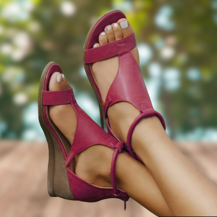 Tendance, coloris bordeaux/framboise, à brides ouvertes et semelle compensée marron, portées aux pieds en extérieur.
