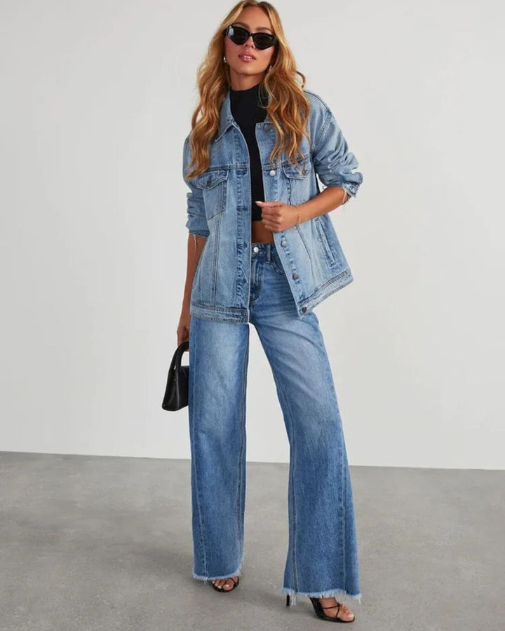 Look complet avec le pantalon taille haute Zephyra pour femme en jean bleu, coupe large moderne, associé à une veste en denim, un top noir, des sandales à talons et des lunettes de soleil.